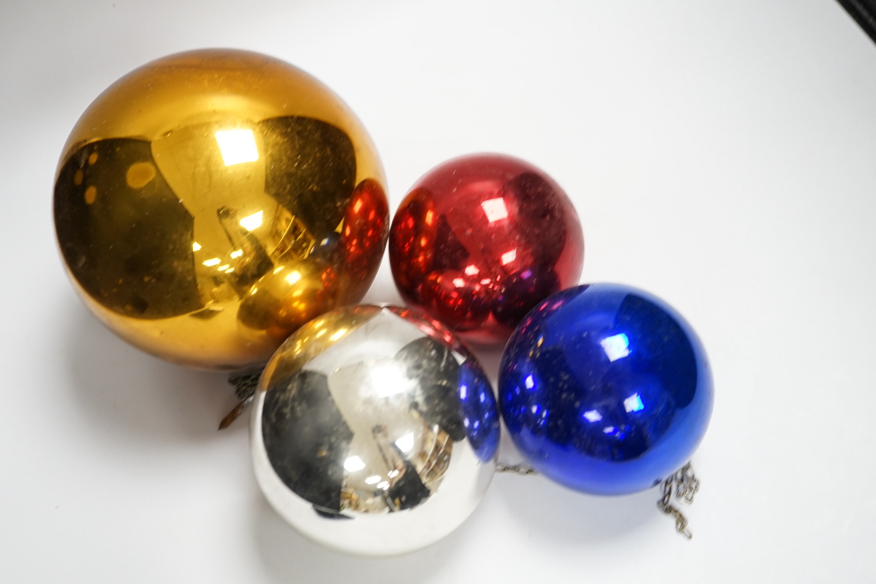 A gold witch’s ball and three small witch’s balls (silver, red and blue)